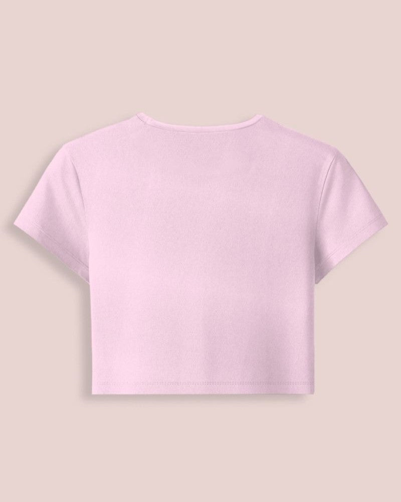 A light pink short-sleeve crop top shown from the back, displayed on a solid pale beige background.