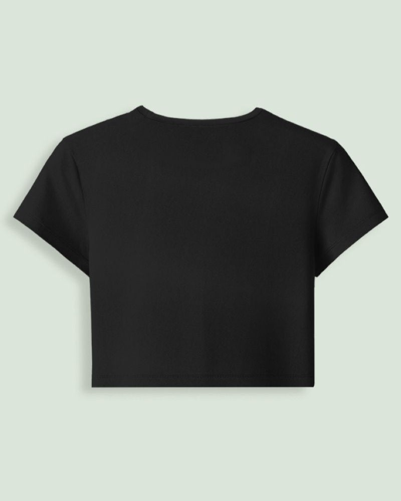 A black short-sleeve crop top t-shirt from back side displayed against a light sage green background.