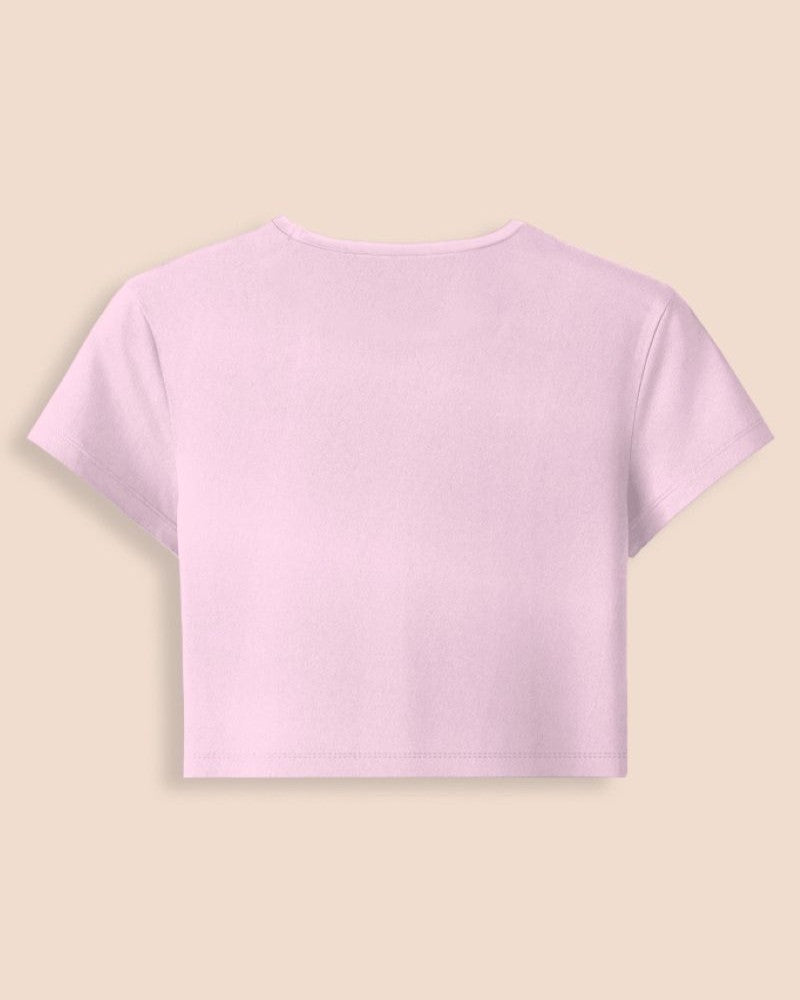 A light pink short-sleeve crop top shown from the back, centered on a solid beige background.