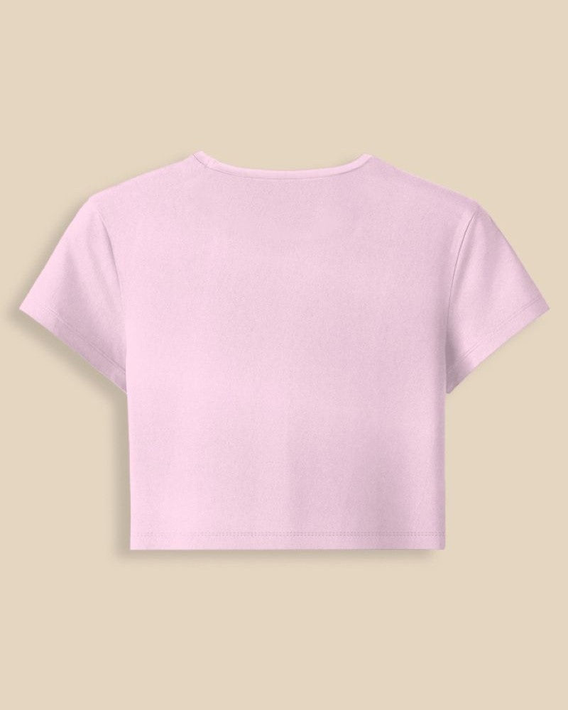 A light pink short-sleeve crop top shown from the back, centered on a solid beige background.