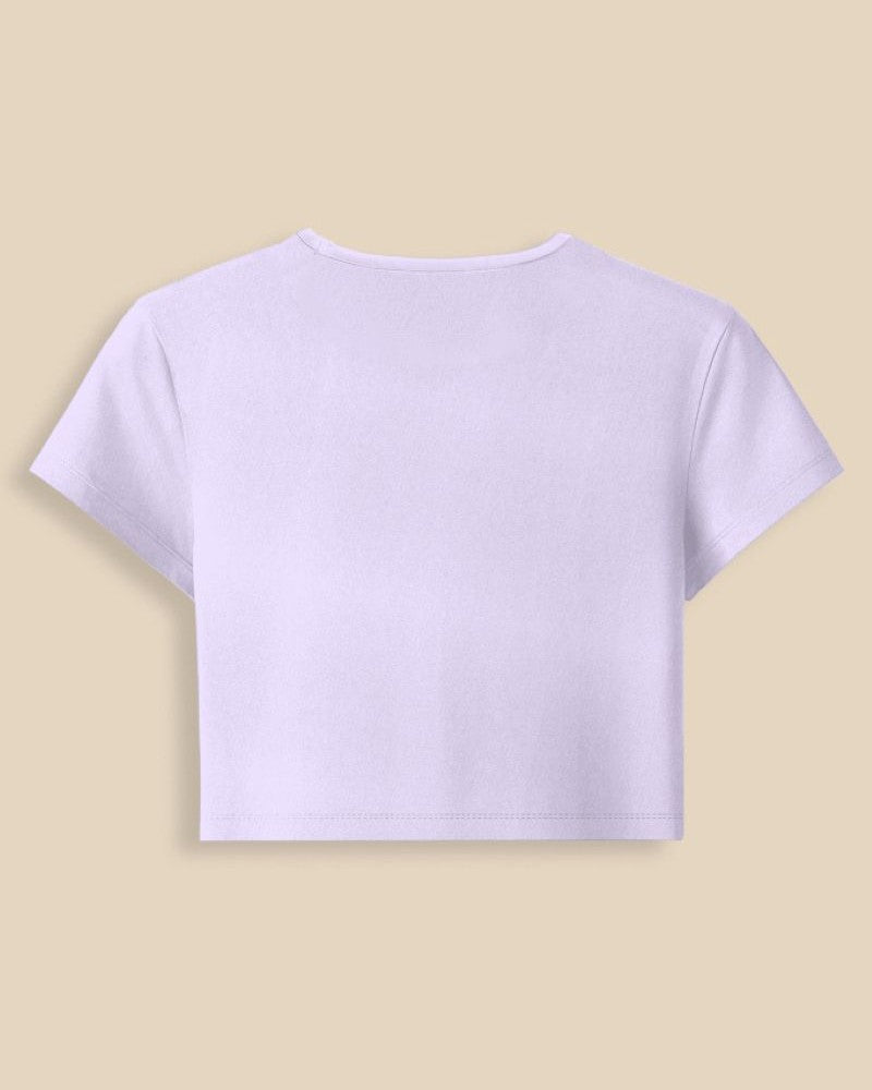 A light lavender short-sleeve crop top shown from the back, laid flat against a solid beige background.