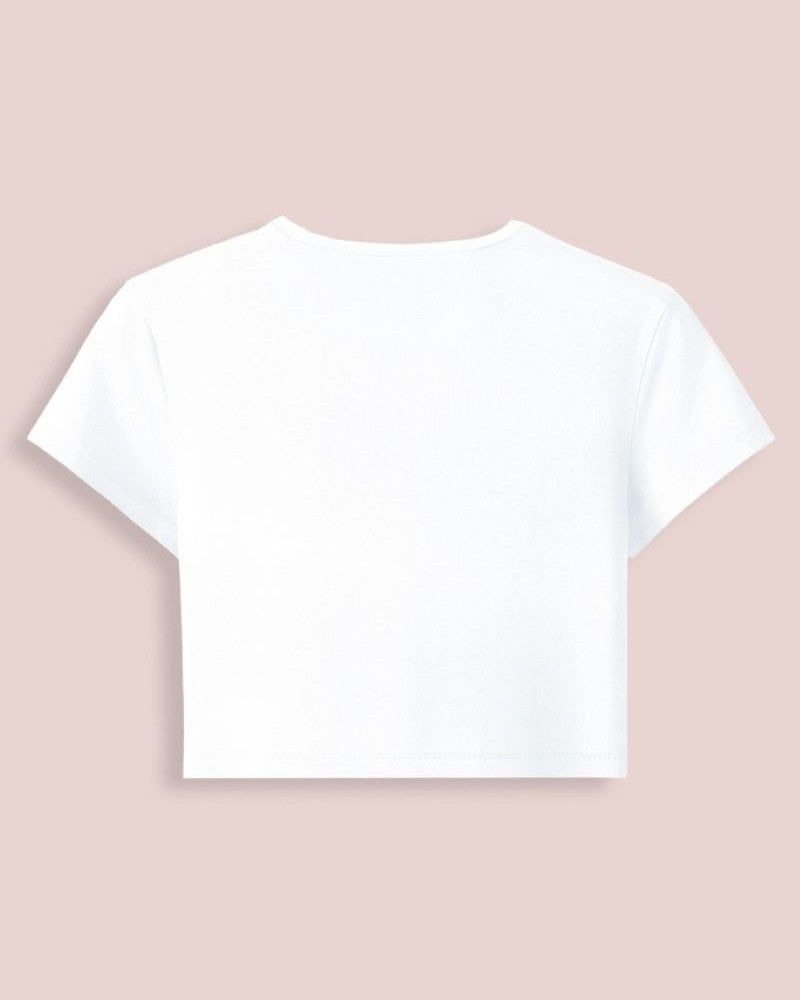 A white short-sleeve crop top shown from the back, centered on a solid pale pink background.