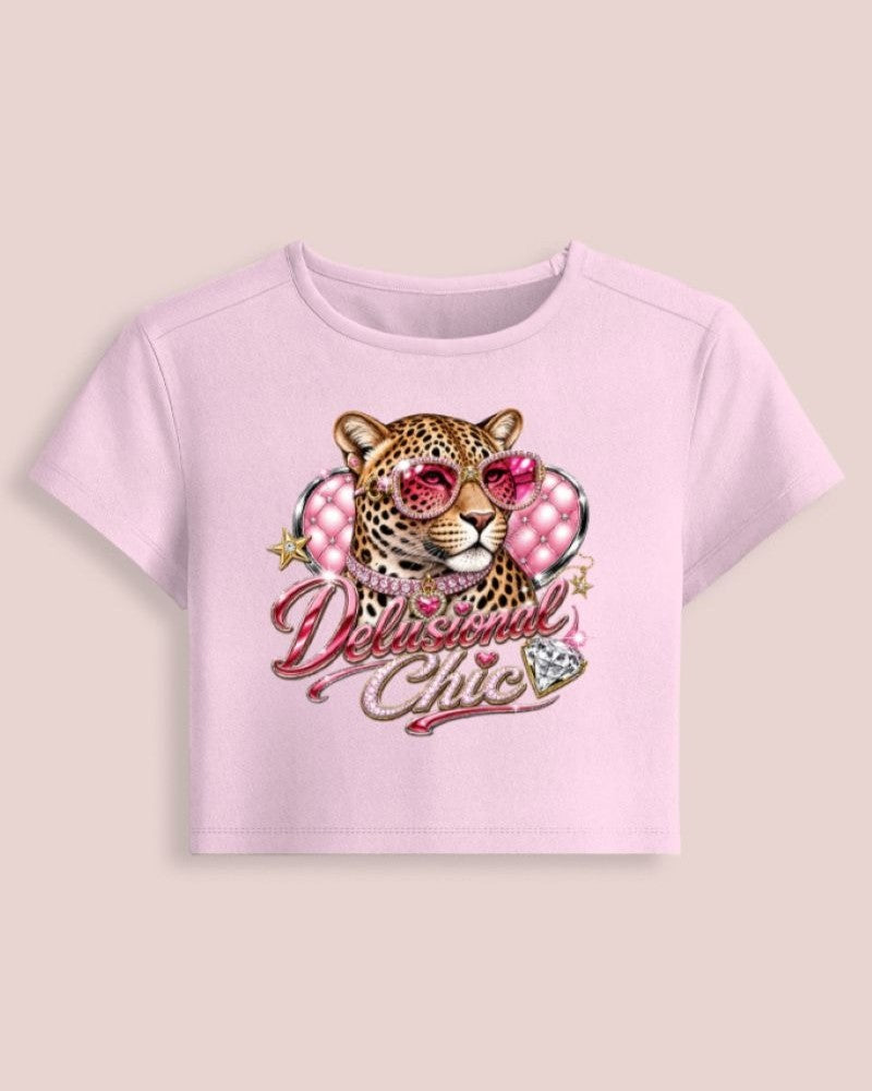 A light pink short-sleeve crop top featuring a graphic of a leopard wearing pink sunglasses, surrounded by pink rhinestones and the text 'Delilah Chic' in pink script, displayed on a solid light beige background.